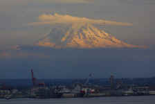MtRainier- watches on high- an inbound jet, an outbound tug, clouds on the run, and the sun disappearing over the horizon as Harbor Island, the container port, the cement plant, and Boeing Field vanish for the night.